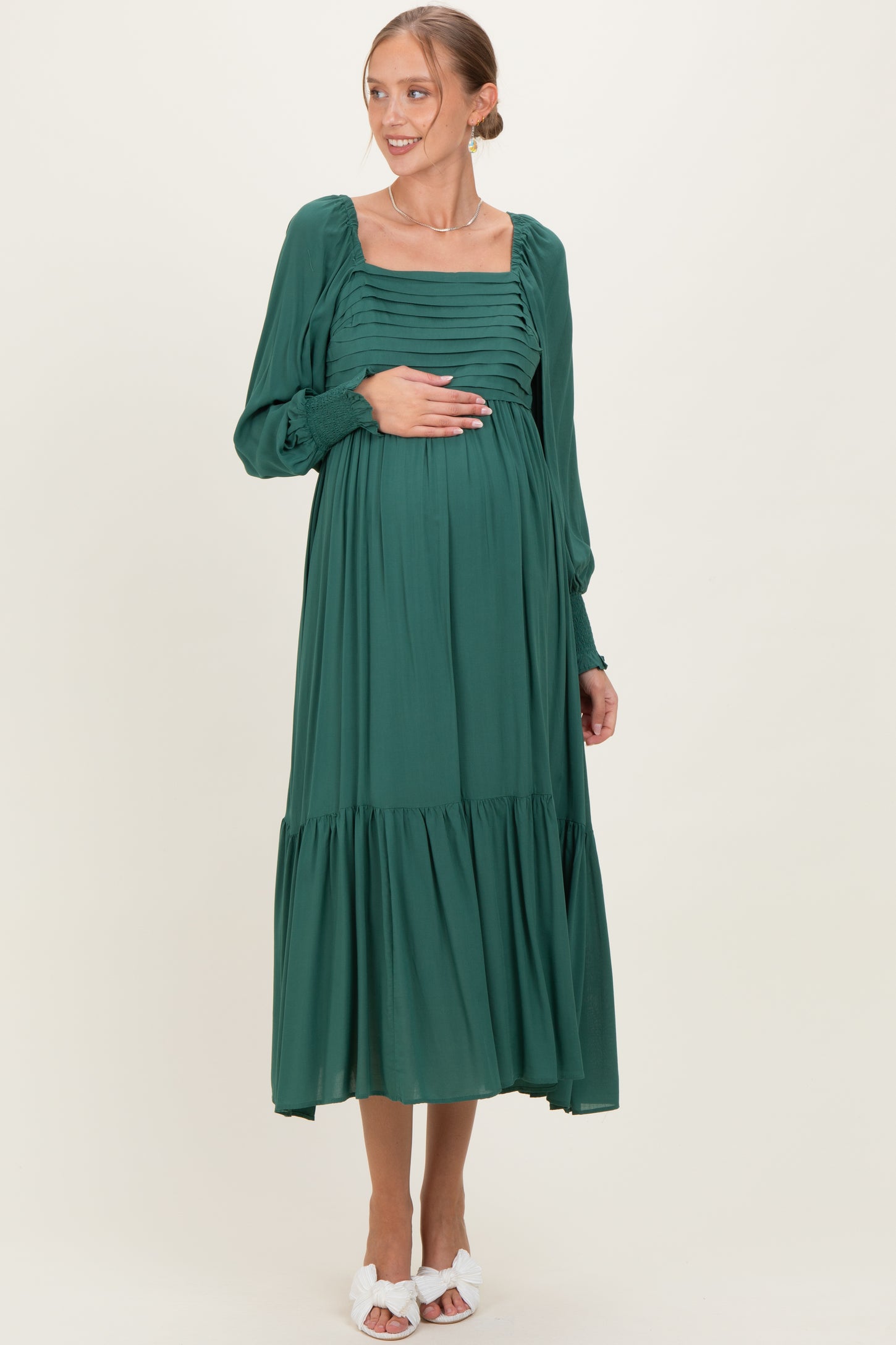woman wearing a dark green maternity maxi dress with puffed sleeves and gathered bodice, showing her baby bump
