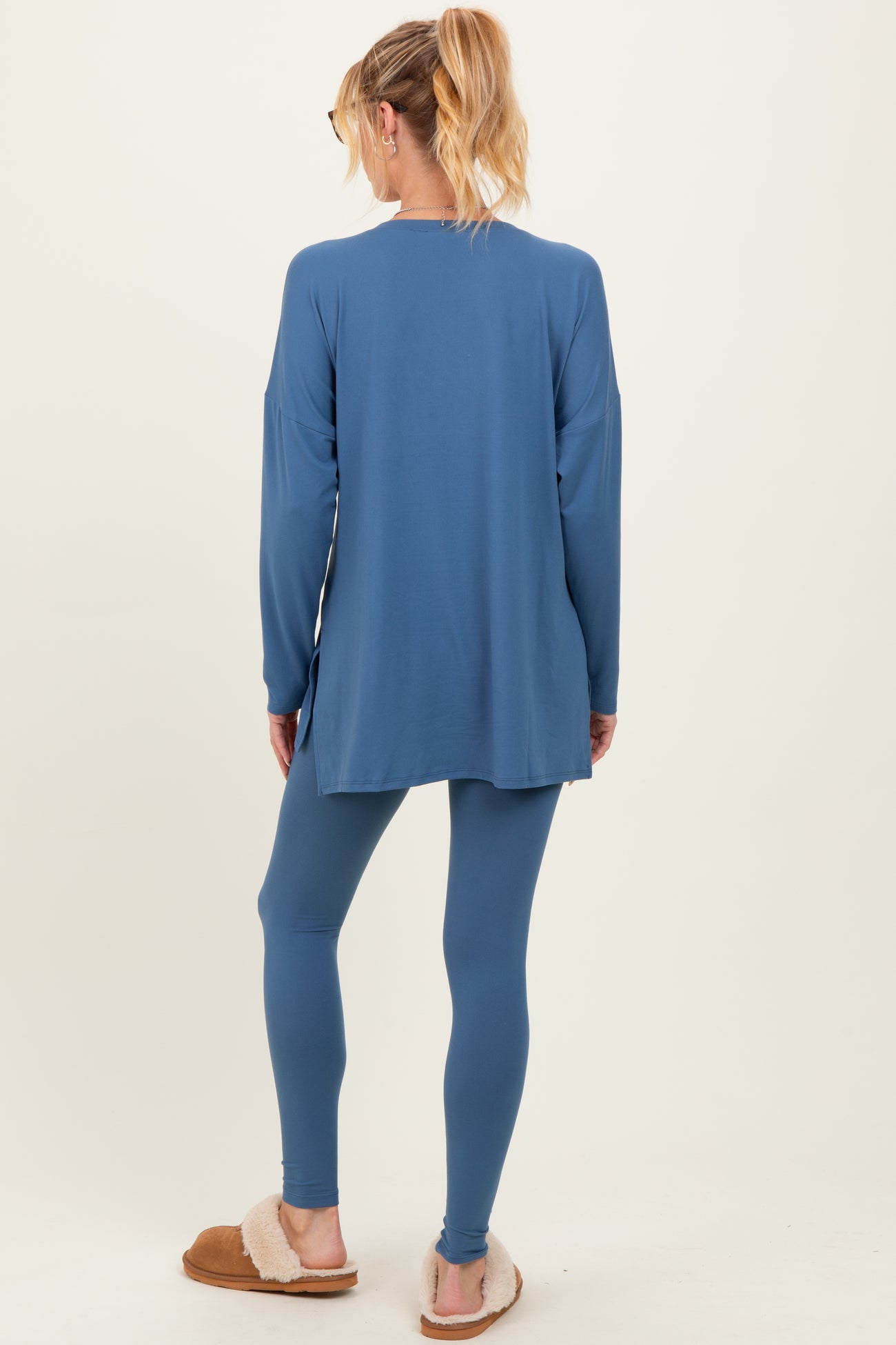 woman wearing a blue maternity tunic and leggings, standing with her back to the camera, showing a relaxed fit