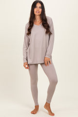 woman wearing a taupe long sleeve loungewear top and matching leggings, standing barefoot on a light background