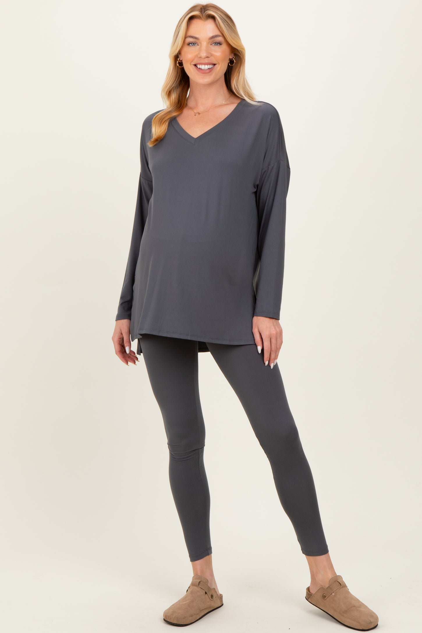 woman wearing a gray maternity top with a v-neck and matching leggings, showcasing her baby bump