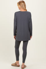 woman wearing a gray long sleeve maternity top and matching leggings, viewed from the back