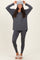 woman wearing a dark gray long sleeve top with a v-neck, matching leggings, and a knit beanie, styled with slippers