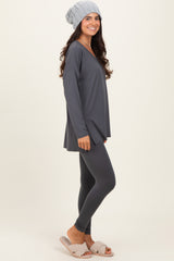 woman wearing a dark gray long sleeve top with leggings and a beanie, standing in a relaxed pose