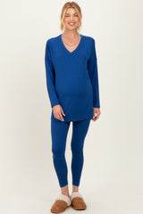 woman wearing a blue maternity loungewear set with a v-neck long sleeve top and matching leggings, showing a baby bump