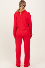 woman wearing a red long sleeve maternity pajama set with white piping details