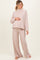 woman wearing a light pink ribbed long sleeve maternity top and matching wide-leg pants, gently cradling her baby bump