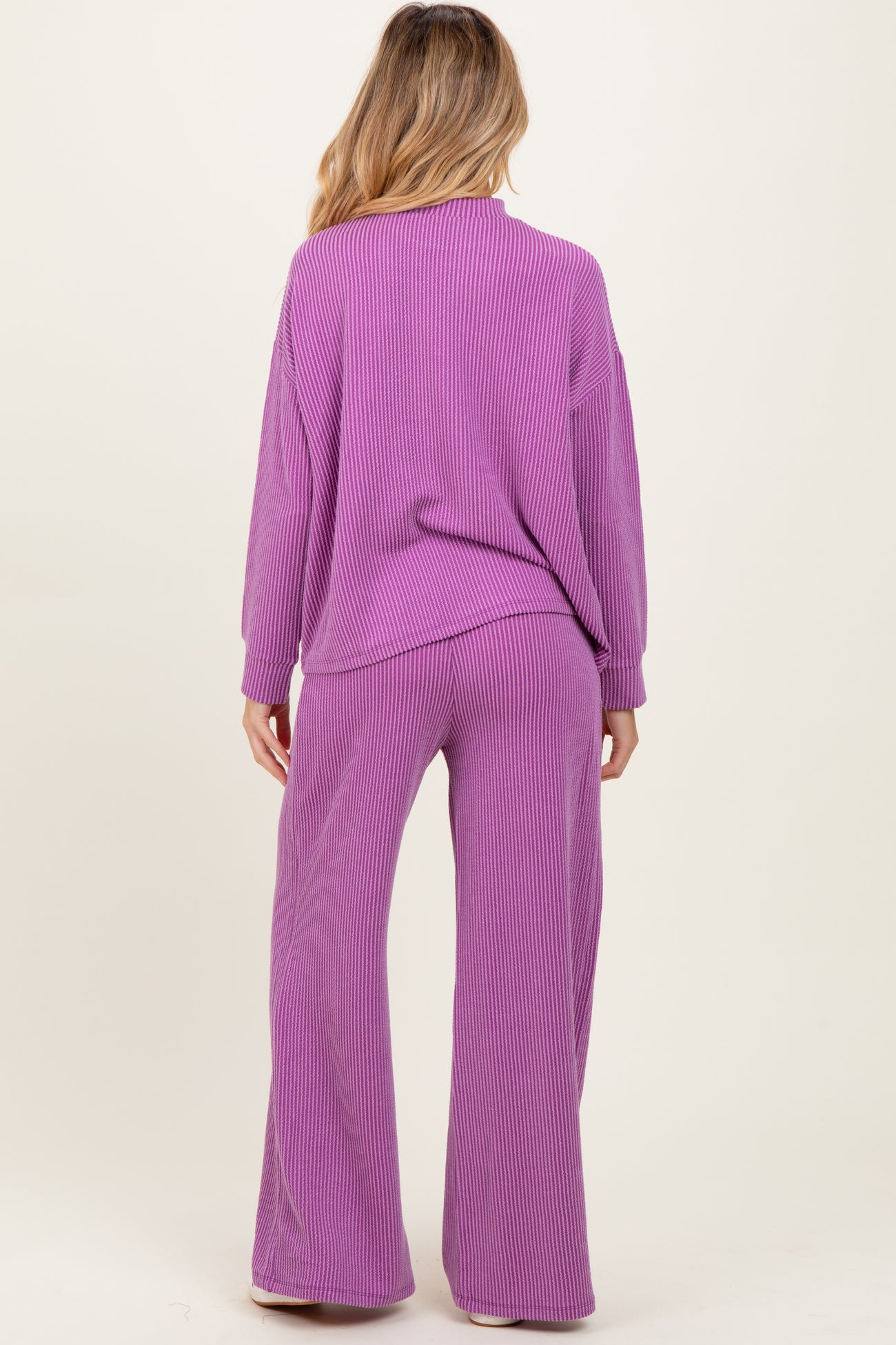 woman wearing a purple ribbed maternity lounge set with long sleeves and wide-leg pants, showing her baby bump