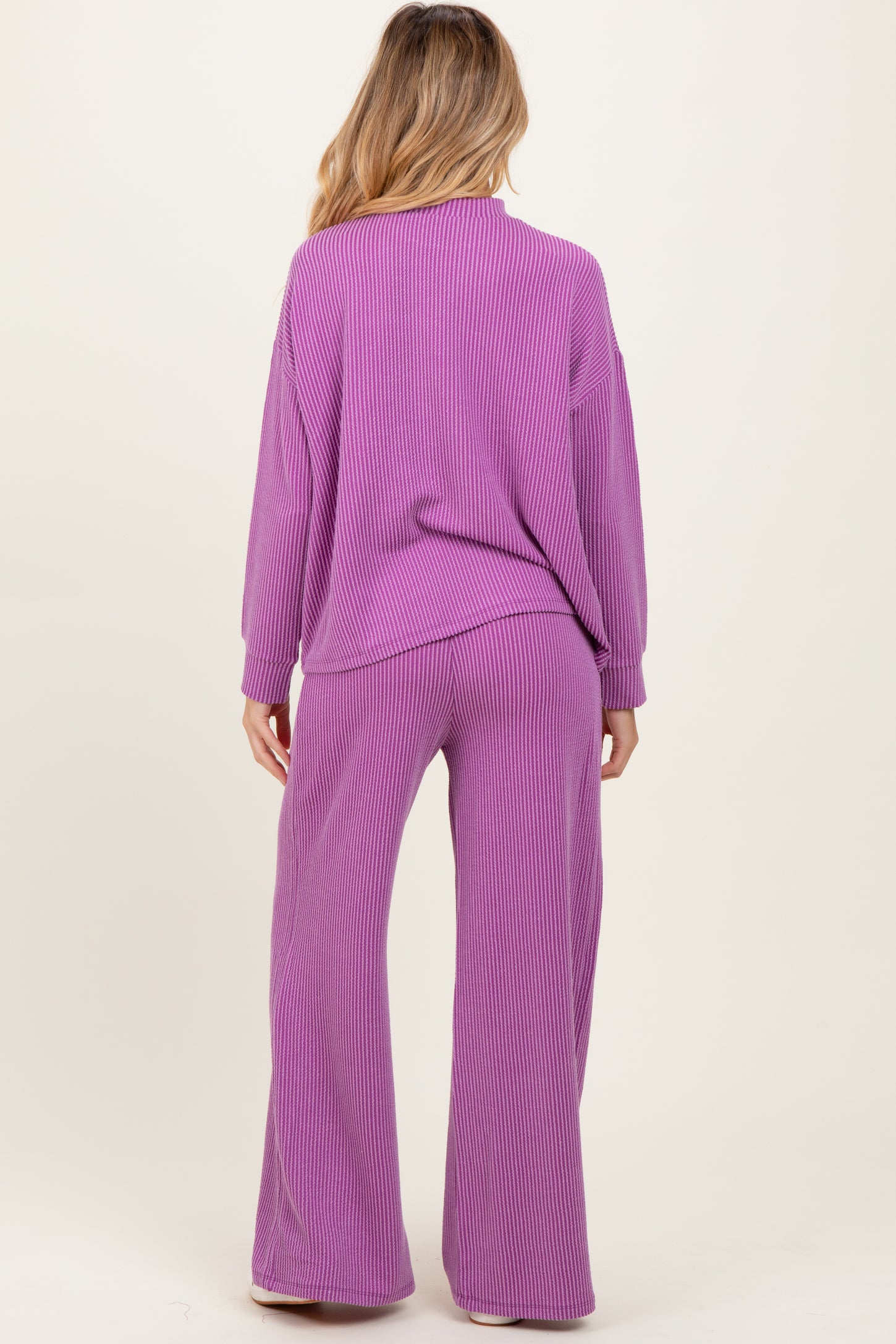 woman wearing a purple ribbed maternity lounge set with long sleeves and wide-leg pants, showing her baby bump