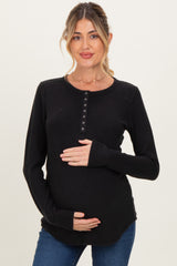 woman wearing a black long sleeve maternity top with button details and holding her baby bump