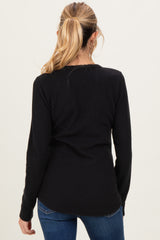 woman wearing a black long sleeve maternity top, viewed from the back, paired with blue jeans