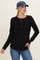 woman wearing a black long sleeve henley top with button details and a blue cap, paired with jeans