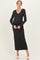 woman wearing a dark shimmer knit maternity dress with a v-neck and long sleeves, showing her baby bump