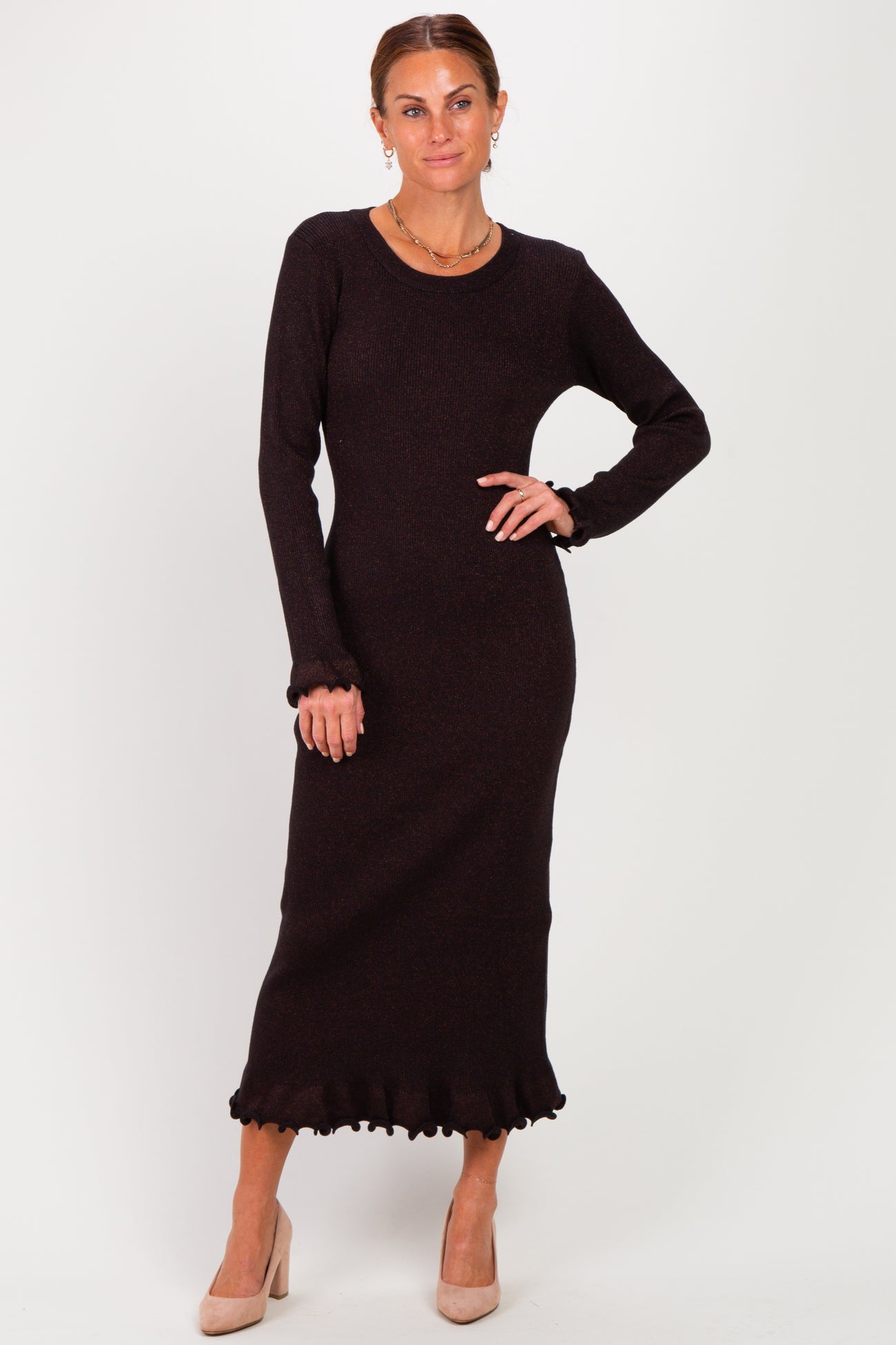 woman wearing a black long sleeve ribbed knit dress with ruffled hem and a fitted silhouette