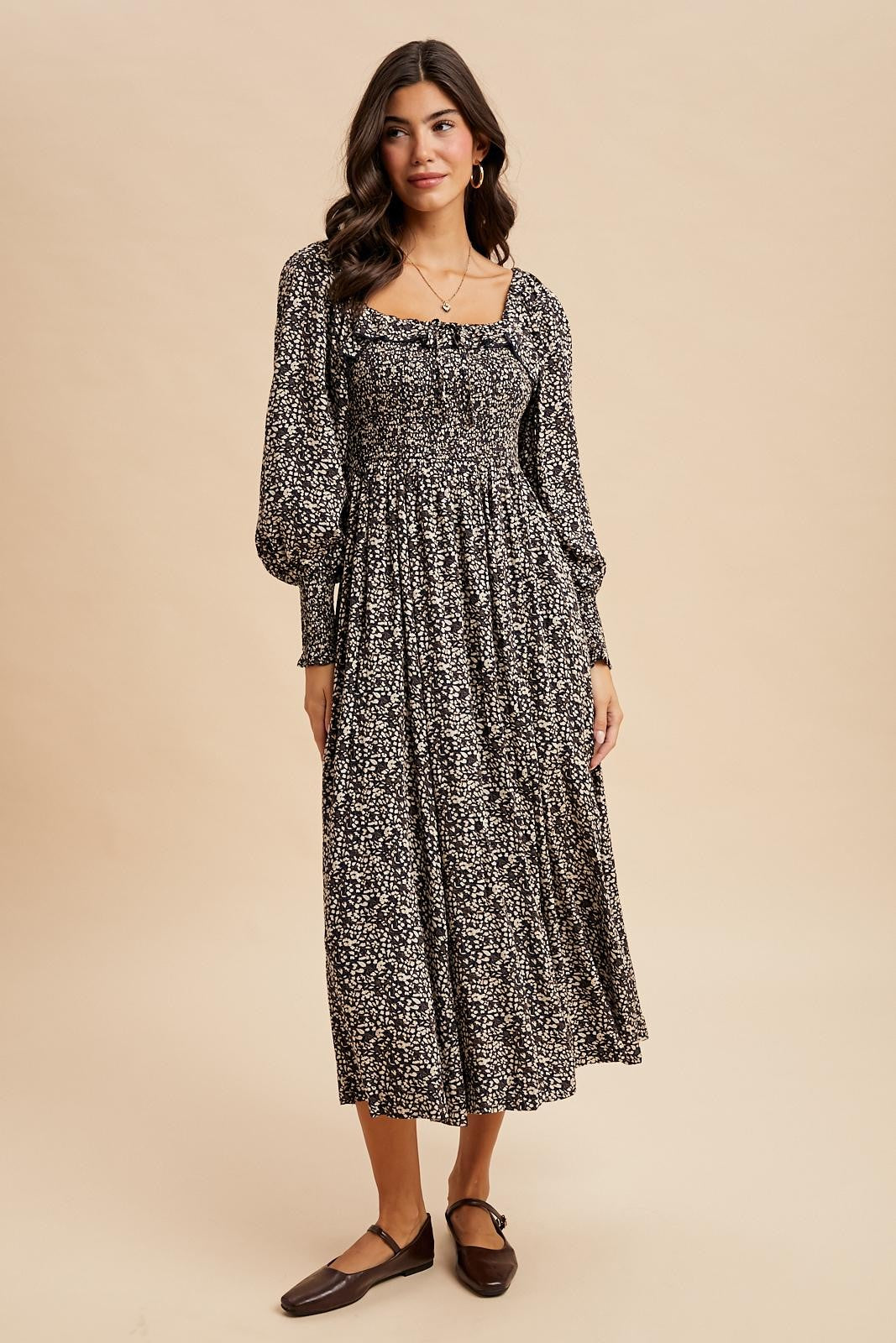 woman wearing a black floral maxi dress with puff sleeves and a smocked bodice