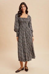 woman wearing a black floral maxi dress with puff sleeves and a smocked bodice