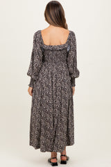 woman wearing a black floral maternity dress with puffed sleeves and a smocked back, showing her baby bump.