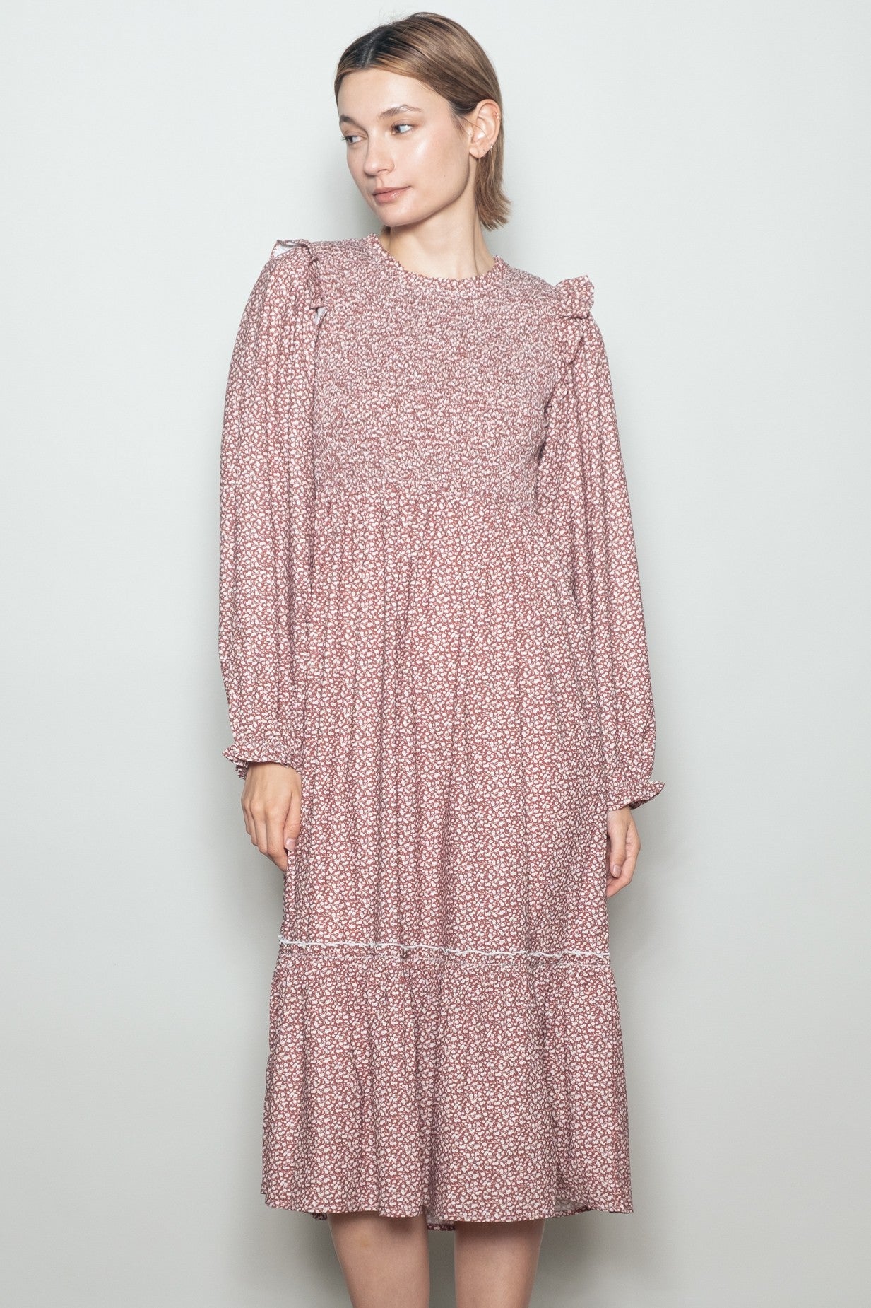 woman wearing a pink floral long sleeve dress with ruffle details and a tiered skirt