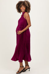 woman wearing a plum pleated maternity dress with a halter neck and holding her baby bump