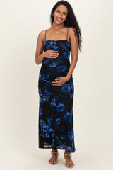 woman wearing a black floral midi maternity dress with ruched detailing and spaghetti straps, holding her baby bump
