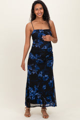 woman wearing a black floral maternity dress with spaghetti straps and ruching, holding her baby bump