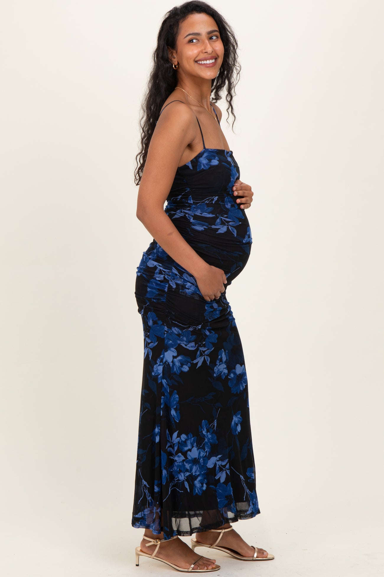 woman wearing a black floral maternity dress and holding her baby bump
