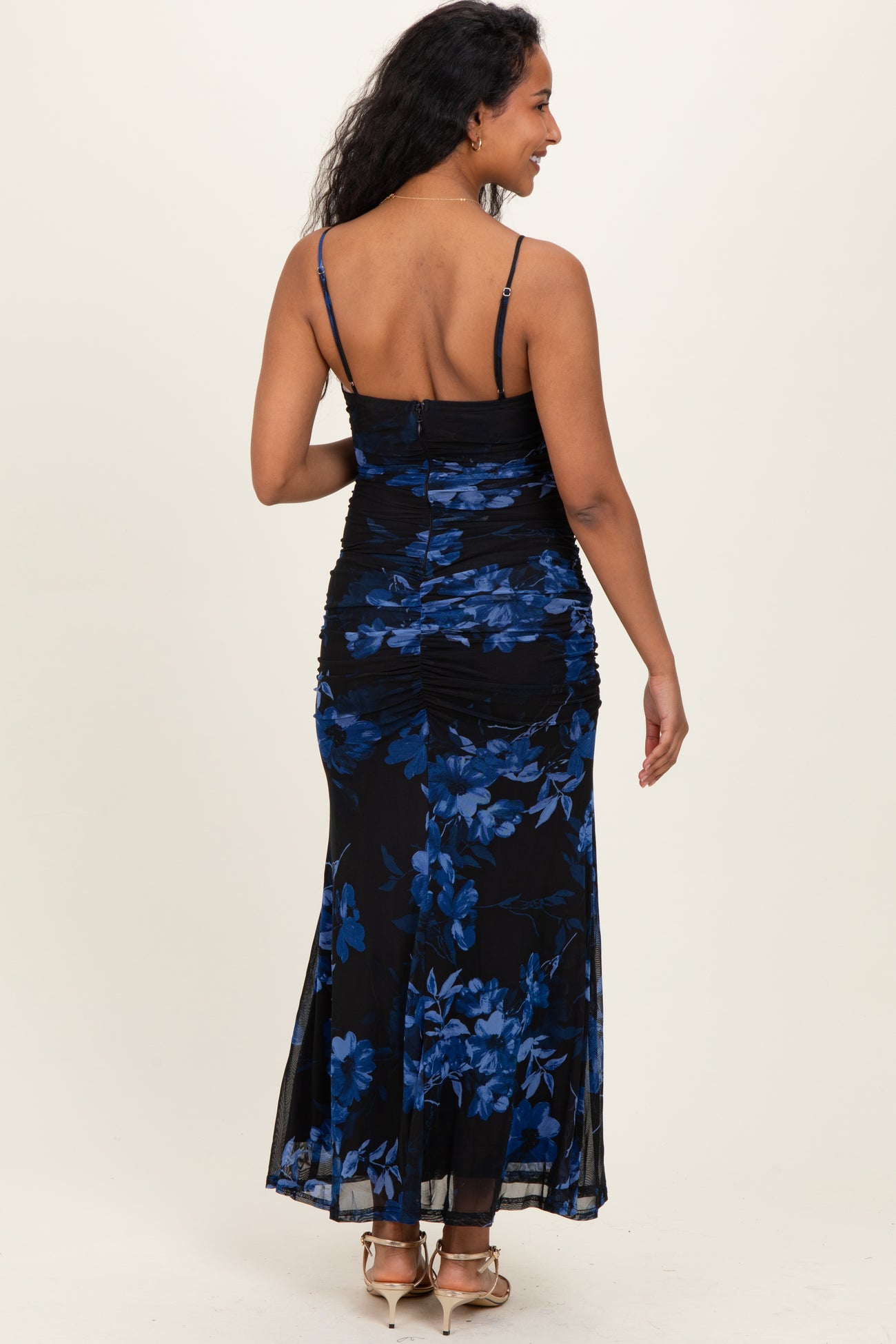 woman wearing a black floral maternity maxi dress with blue flowers and adjustable spaghetti straps, showing a baby bump