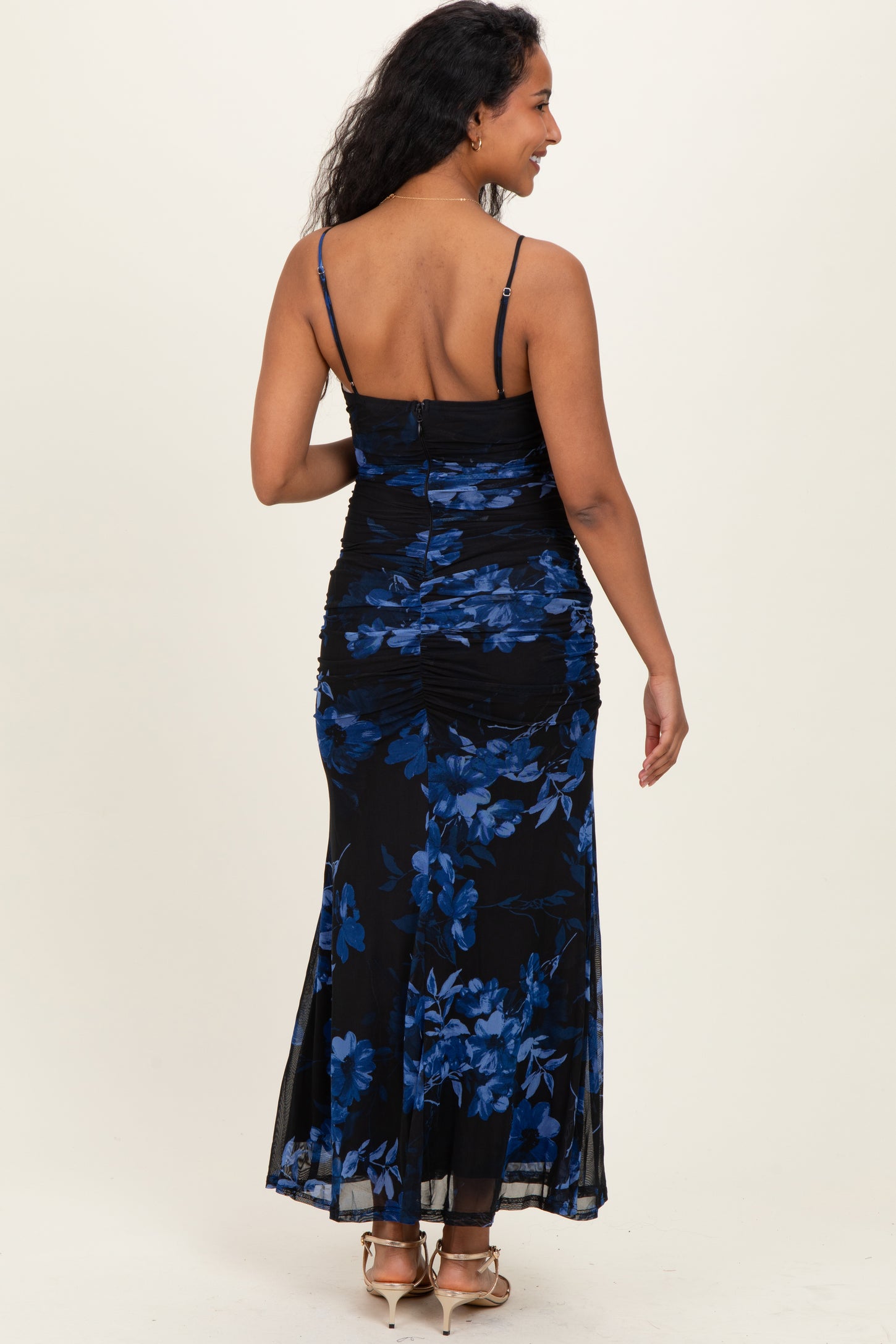 woman wearing a black floral maternity maxi dress with blue flowers and adjustable spaghetti straps, showing a baby bump