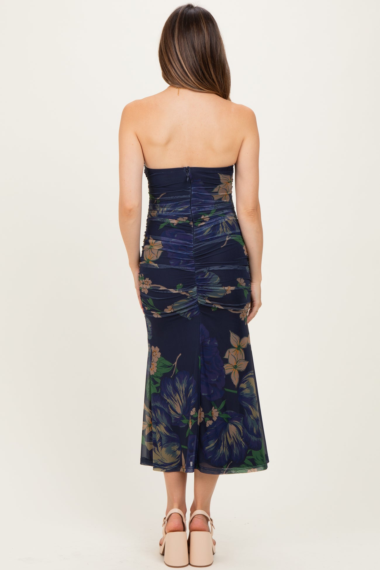 woman wearing a navy floral strapless maternity dress with a fitted bodice and flared hemline, showing a baby bump