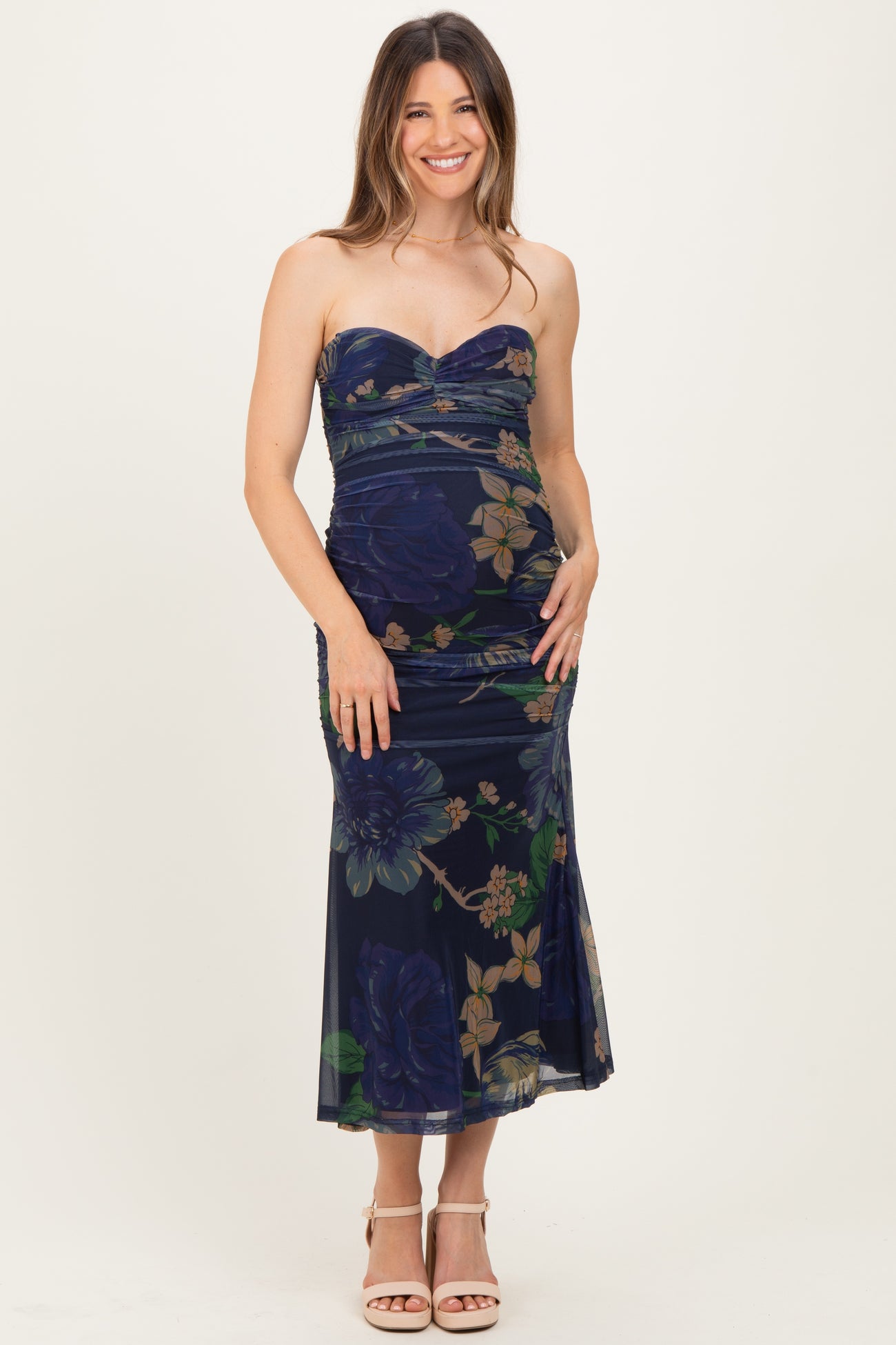 woman wearing a strapless navy blue floral maternity dress and showing her baby bump