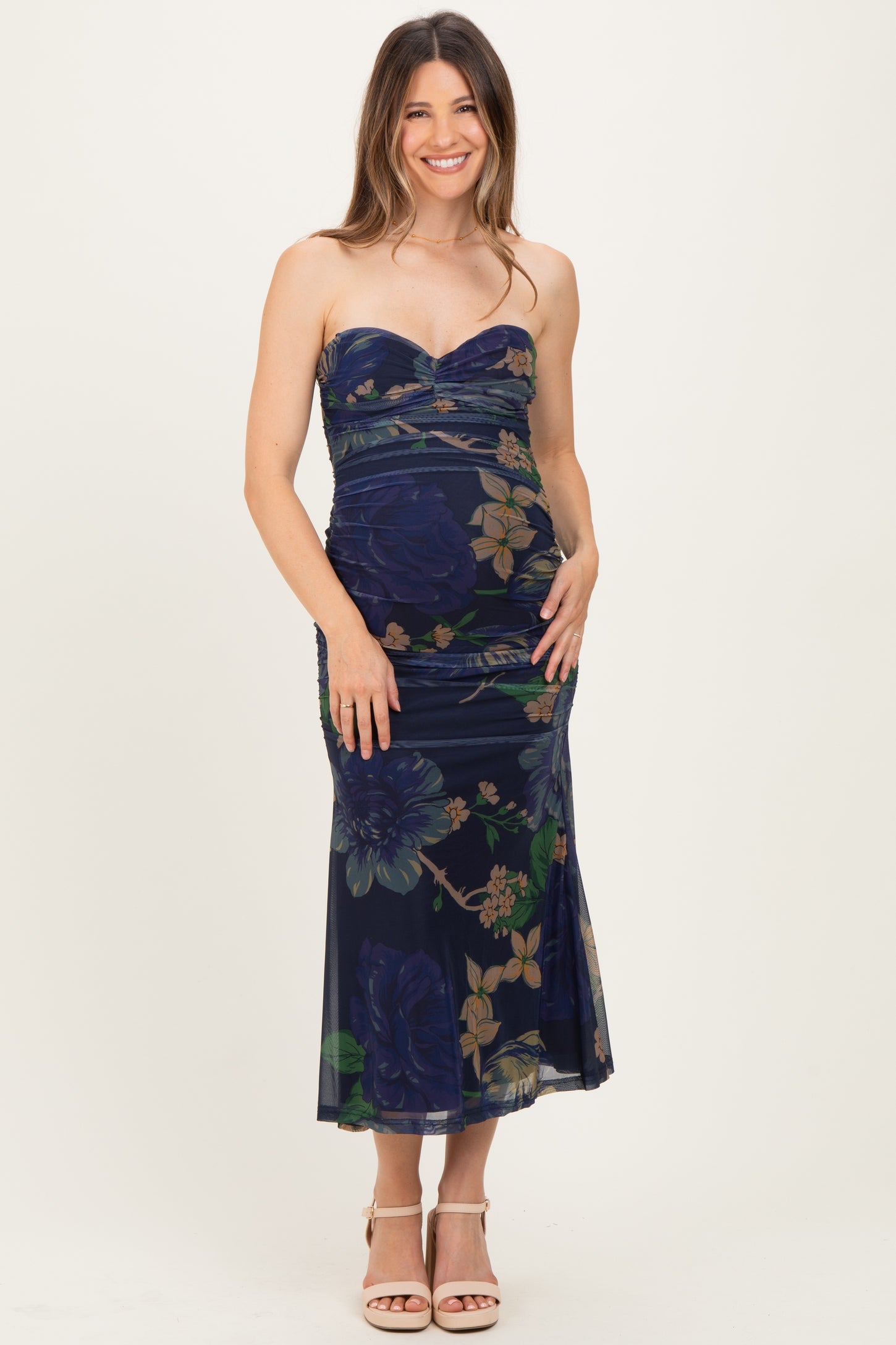woman wearing a strapless navy blue floral maternity dress and showing her baby bump