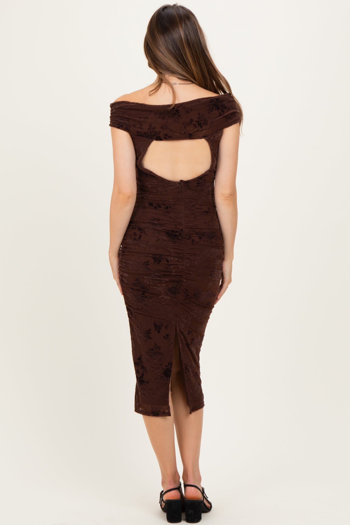 woman wearing a brown maternity dress with off-the-shoulder design and open back details, showing a fitted silhouette