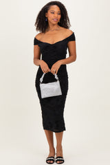 woman wearing a black off-the-shoulder fitted dress with textured details, holding a silver striped handbag