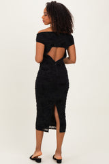 woman wearing a black off-the-shoulder midi dress with a back cutout and ruching details