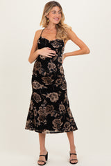 woman wearing a black floral maternity dress with a fitted bodice and flared skirt, holding her baby bump