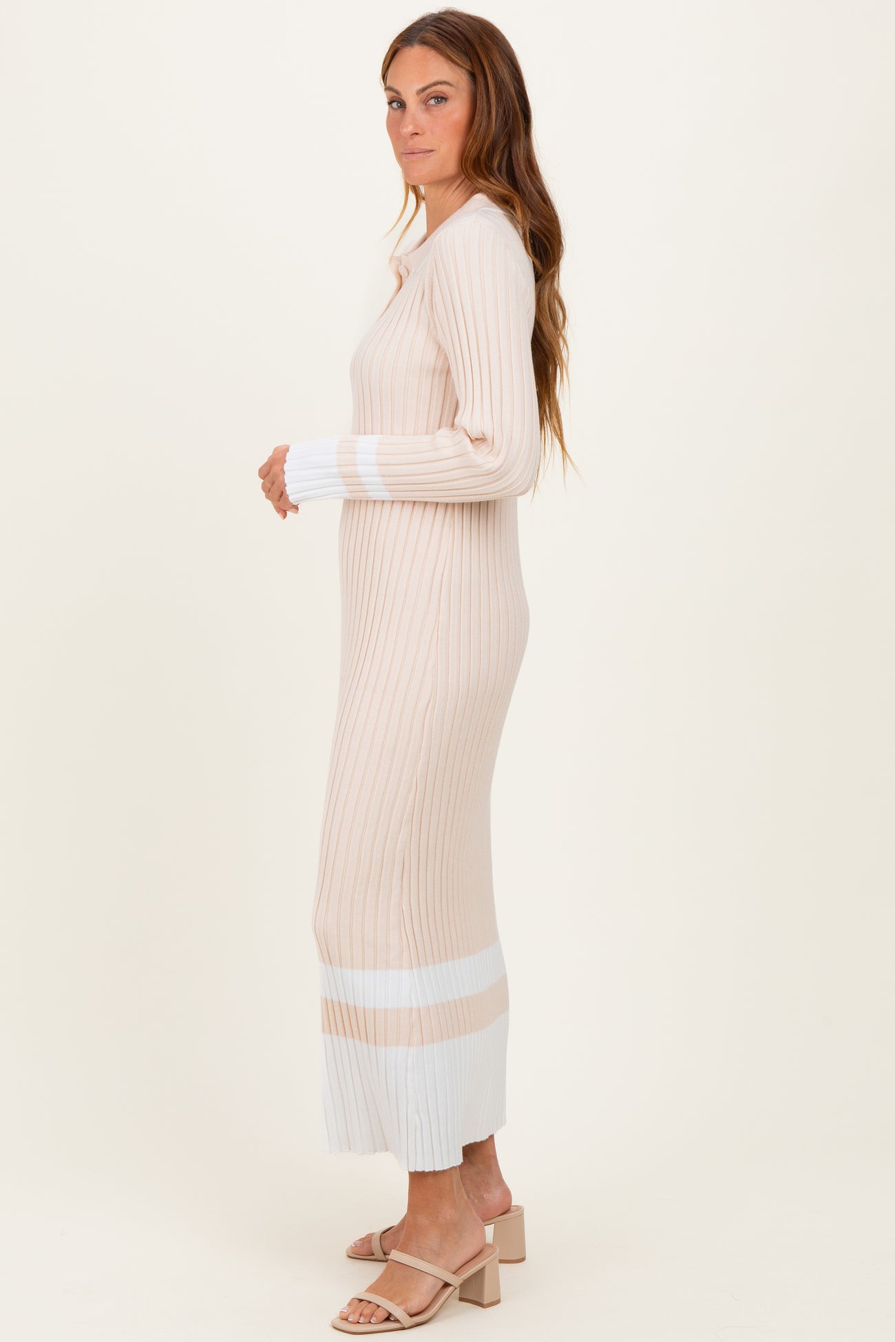 woman wearing a ribbed beige and white long sleeve sweater dress with a fitted silhouette and side slits
