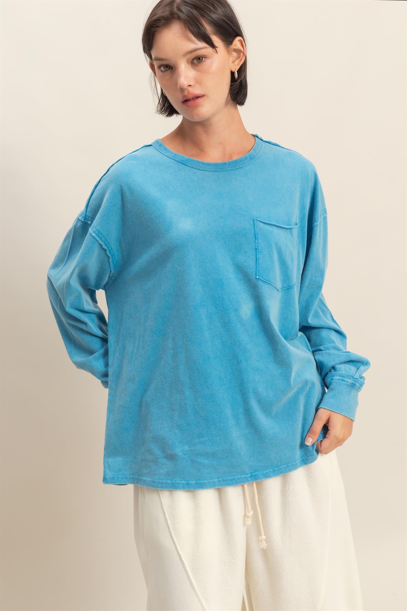 woman wearing an oversized blue long sleeve t-shirt with a front pocket and relaxed fit