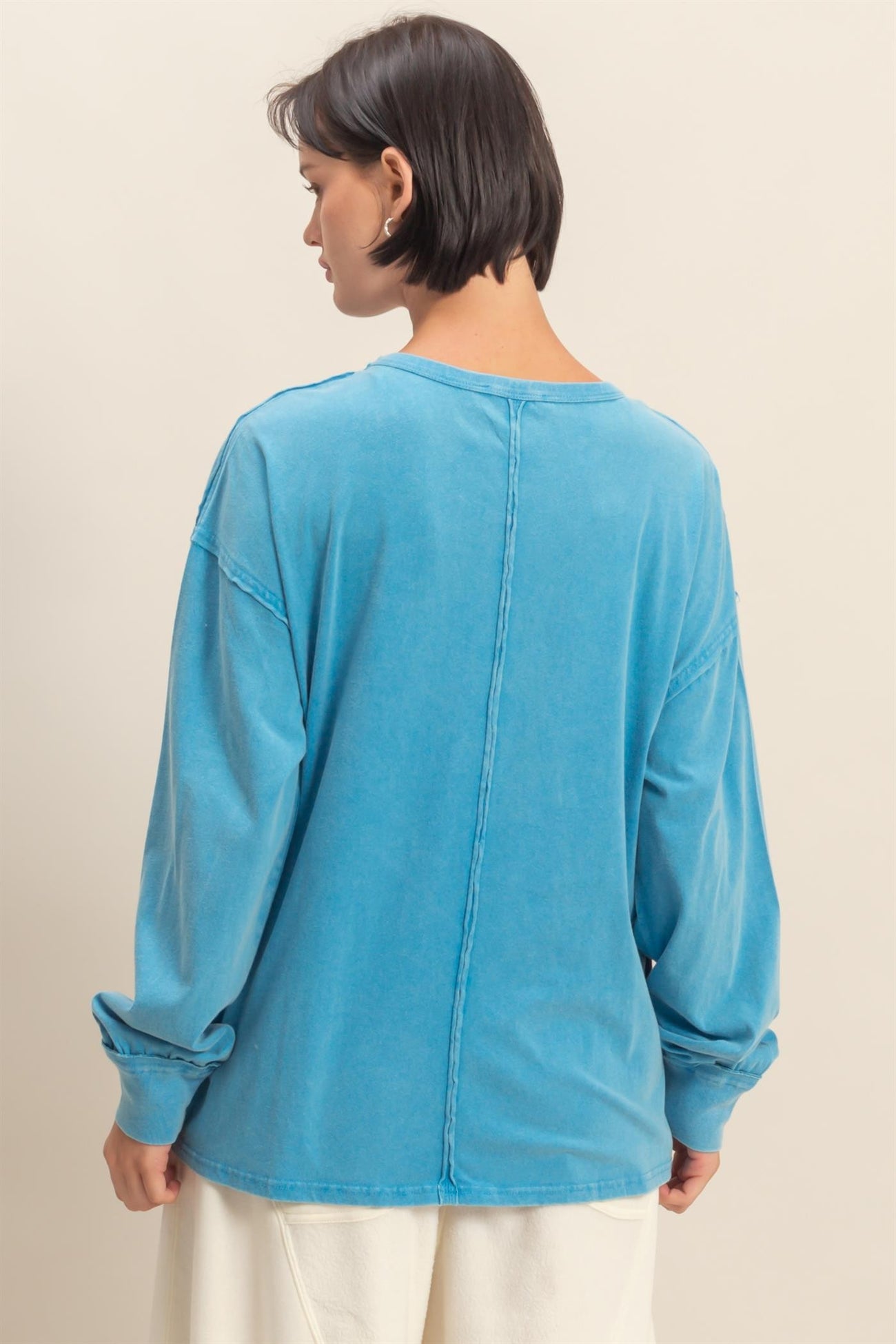 woman wearing a blue oversized long sleeve top with a relaxed fit and seam detail on the back