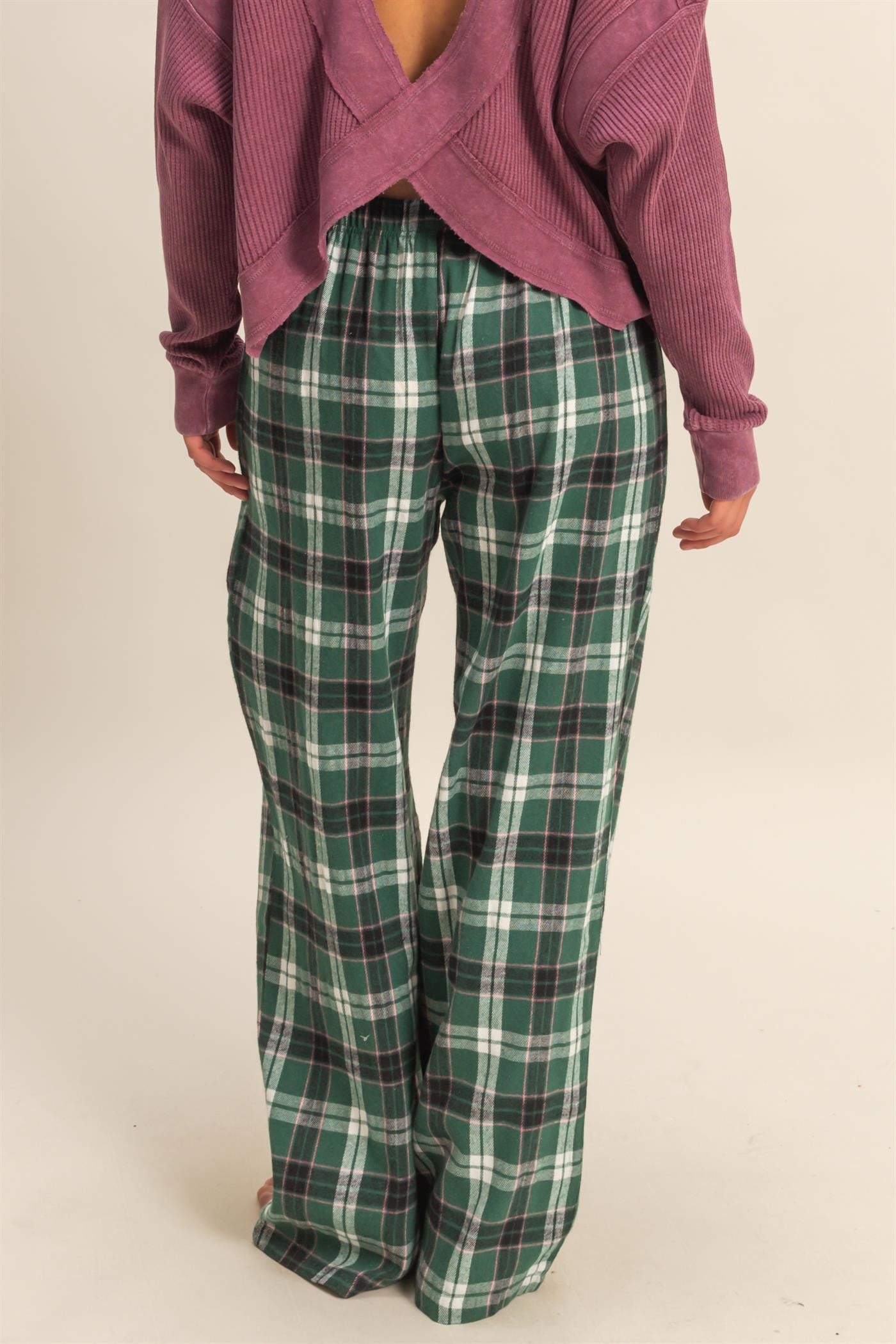 woman wearing a purple oversized sweater and green plaid wide-leg pants, viewed from the back