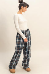 woman wearing a white long sleeve ribbed top and plaid wide-leg pants with side pockets