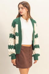 woman wearing a green and white striped knitted cardigan over a white top and brown button-down mini skirt