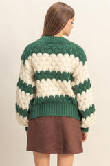 woman wearing a green and cream striped chunky knit sweater from the back with puffy sleeves and a ribbed hem