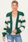 woman wearing a green and white striped chunky knit maternity cardigan and holding her baby bump