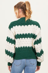woman wearing a green and white striped chunky knit maternity sweater, showing the back and oversized sleeves