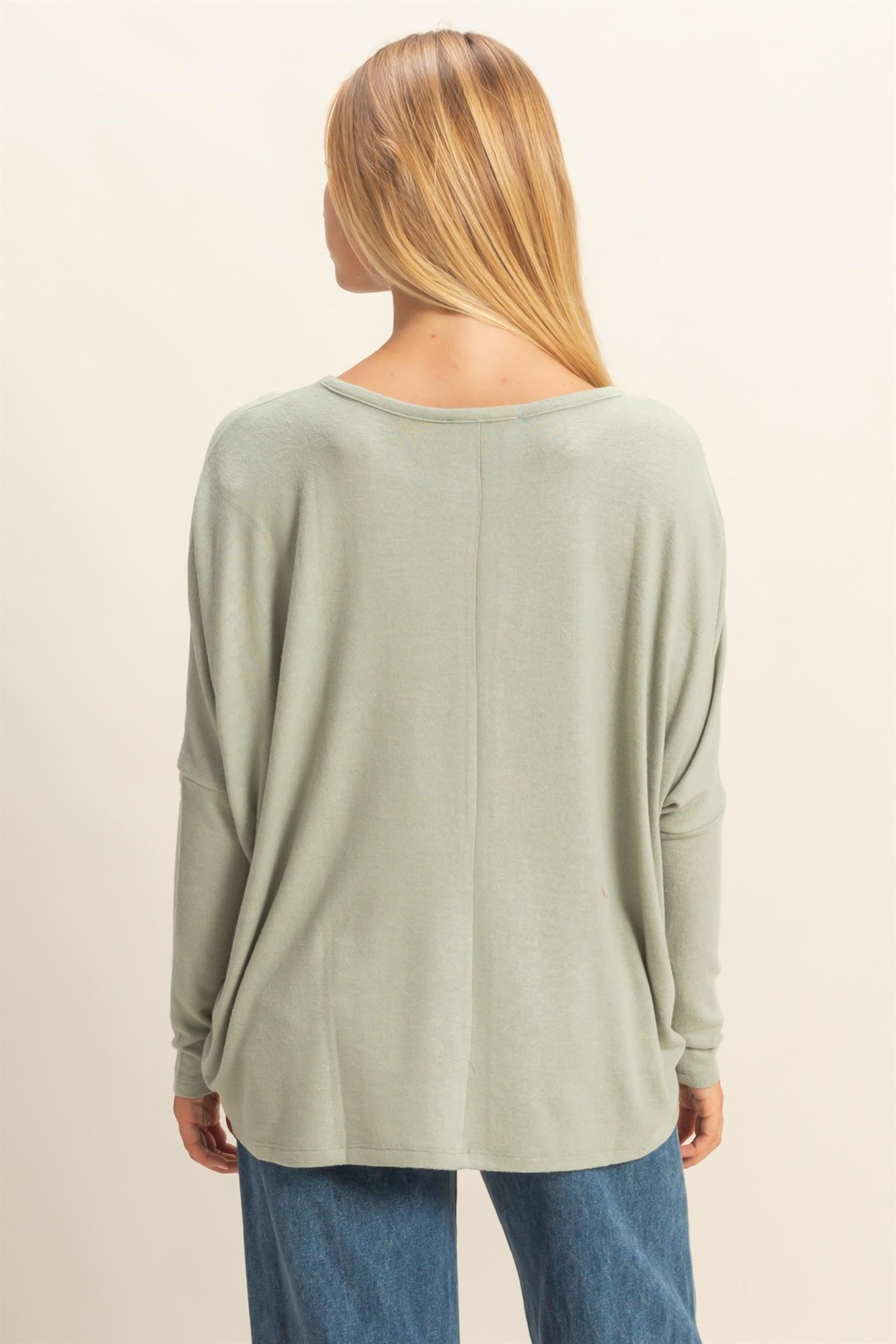woman wearing a light green oversized long sleeve top with a relaxed fit and dropped shoulder seams