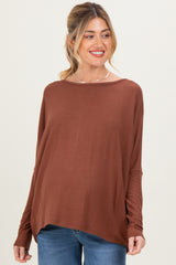 woman wearing a rust colored long sleeve maternity top with a relaxed fit and visible baby bump