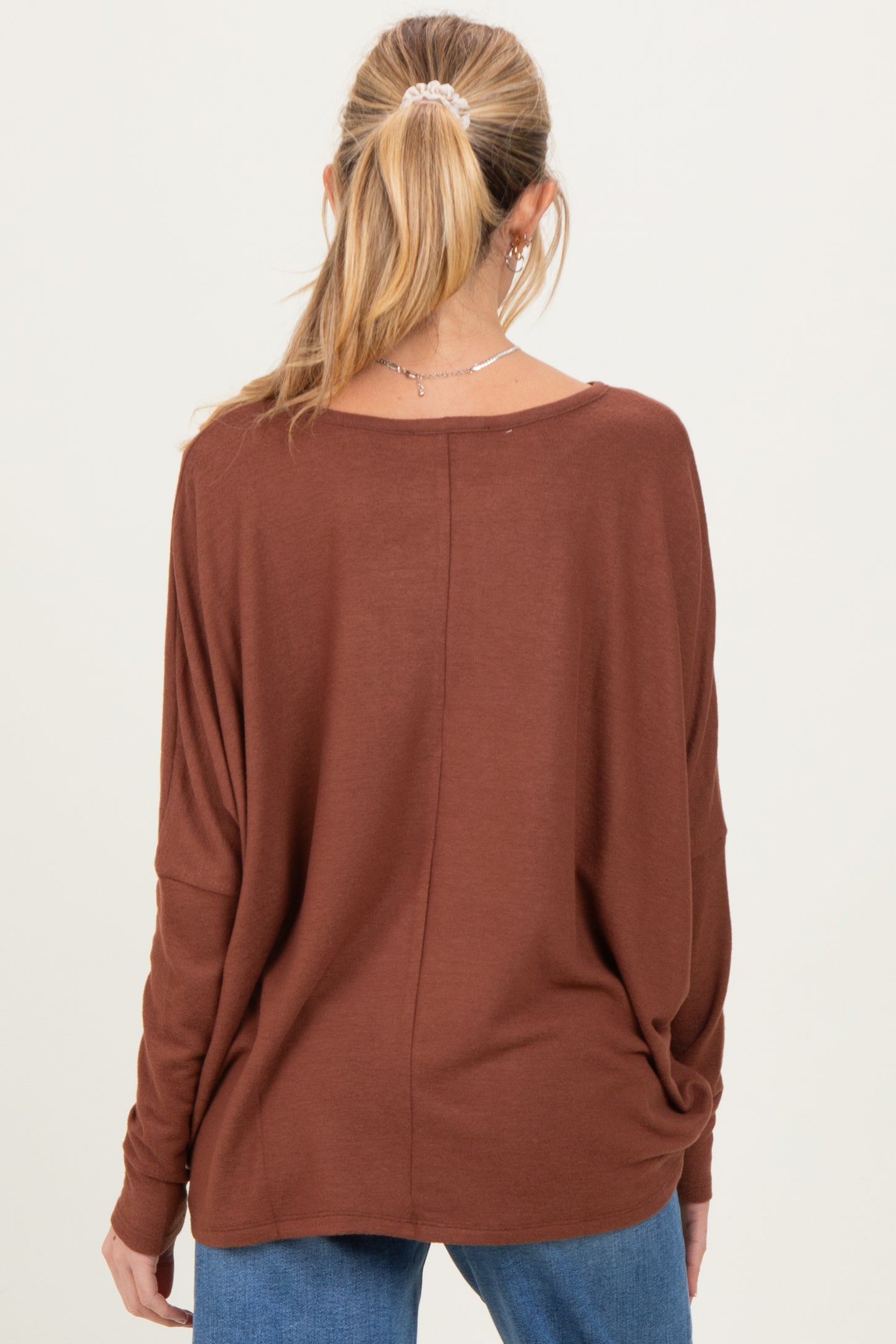 woman wearing a brown long sleeve maternity top with a relaxed fit, seen from the back