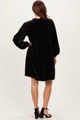 woman wearing a black velvet mini dress with puff sleeves and a gathered waist, view from the back