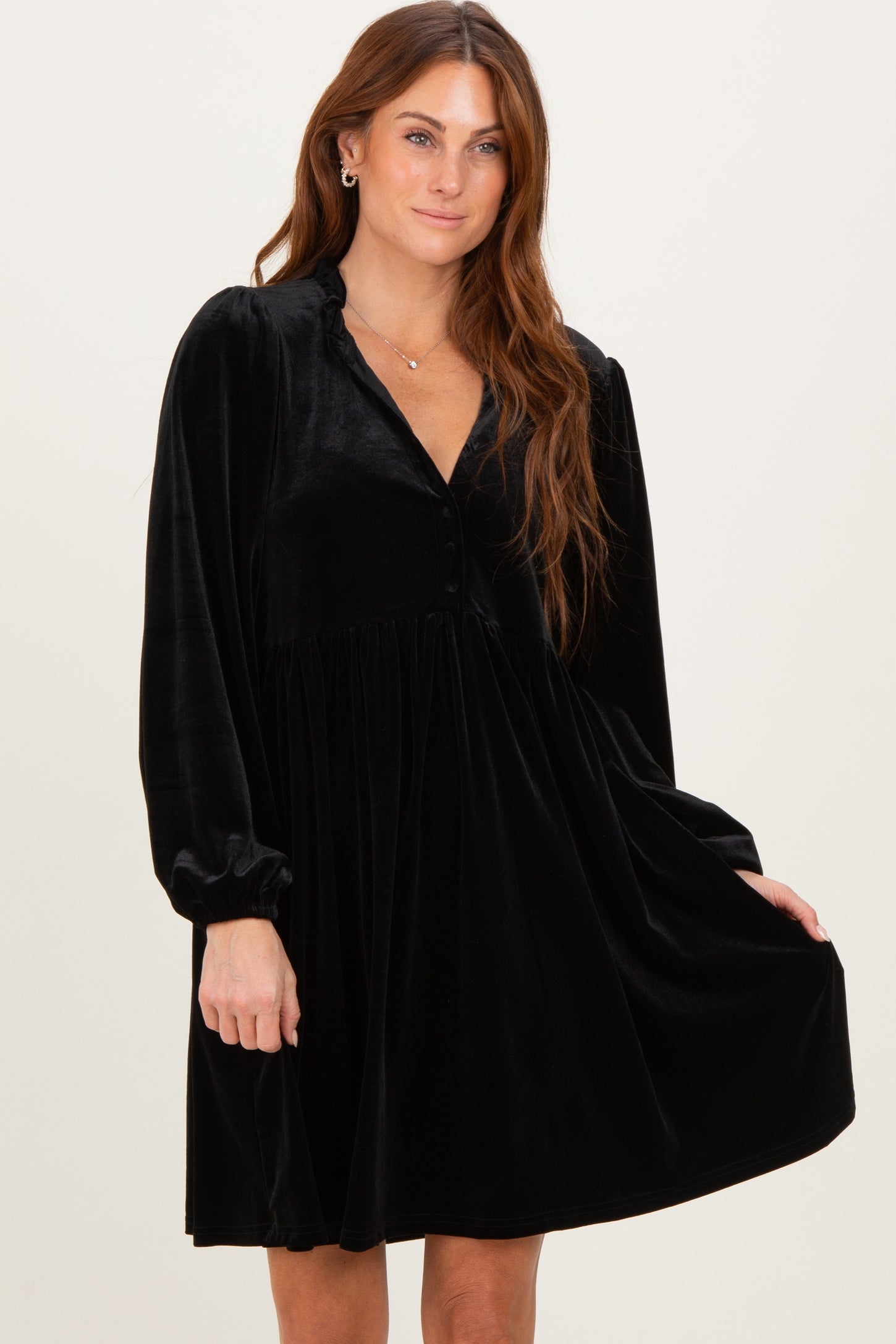 woman wearing a black velvet long sleeve dress with a button-down neckline and a flowy skirt