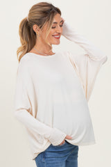woman wearing a light beige maternity top with long sleeves and a visible baby bump