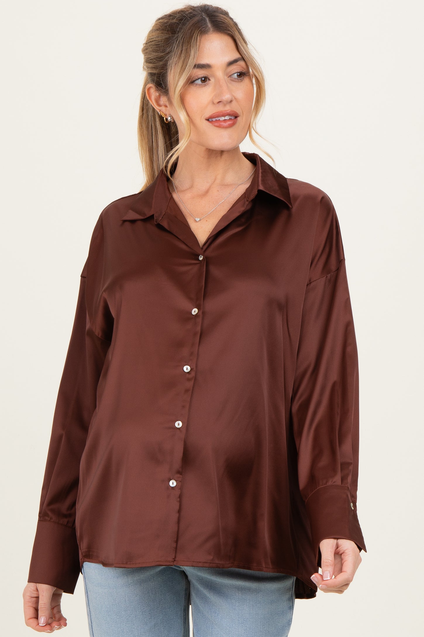 woman wearing a brown satin maternity button-up shirt with a relaxed fit and long sleeves